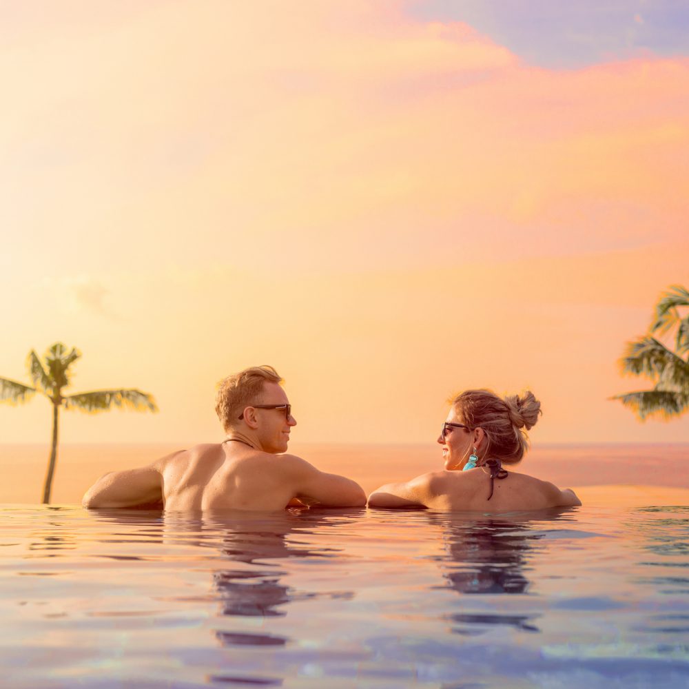 Happy couple on honeymoon in luxury hotel pool